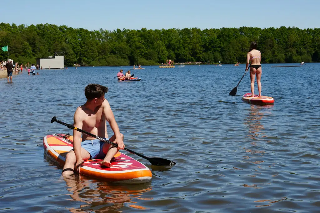 SUP-Fahrer auf dem Otto-Maigler-See mit Badegästen im Hintergrund